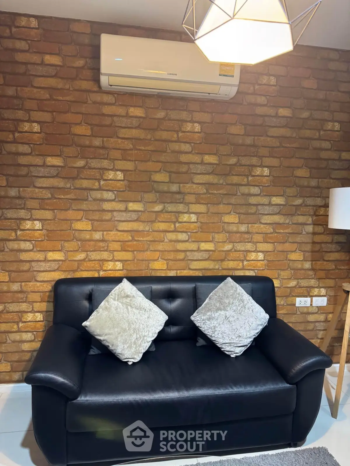 Cozy living room with stylish brick wall and modern black sofa