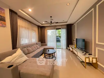 Spacious living room with modern decor and large windows offering garden view.