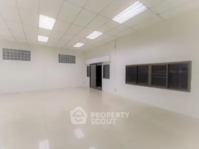 Spacious empty room with tiled flooring and large windows, ideal for office or studio setup.