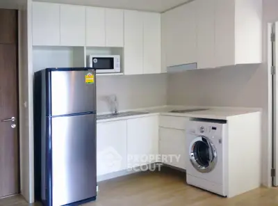 Modern kitchen with sleek appliances including fridge, microwave, and washing machine in a compact layout.