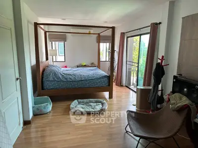 Spacious bedroom with wooden flooring and large windows offering natural light and garden view.