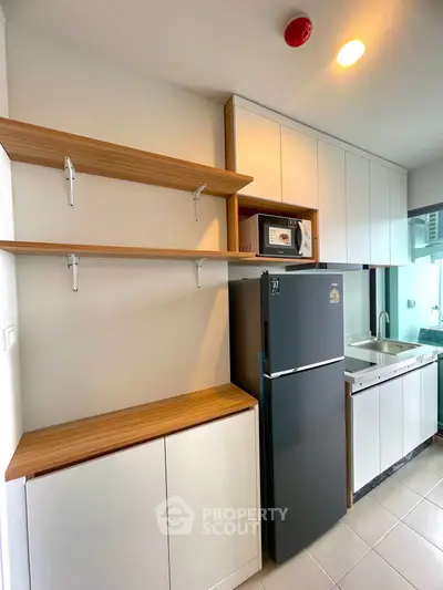 Modern kitchen with sleek cabinets, spacious fridge, and built-in microwave in a contemporary apartment.