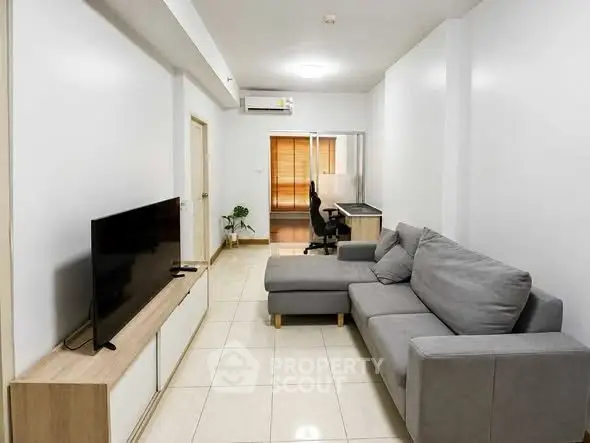 Modern living room with sleek gray sofa and flat-screen TV, perfect for relaxation and entertainment.