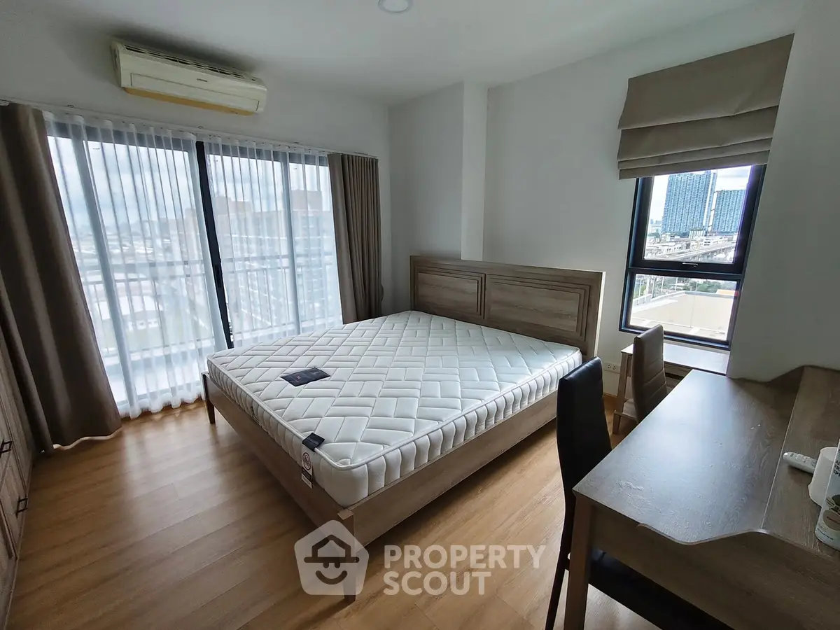 Spacious bedroom with large windows and modern furnishings in a high-rise apartment.
