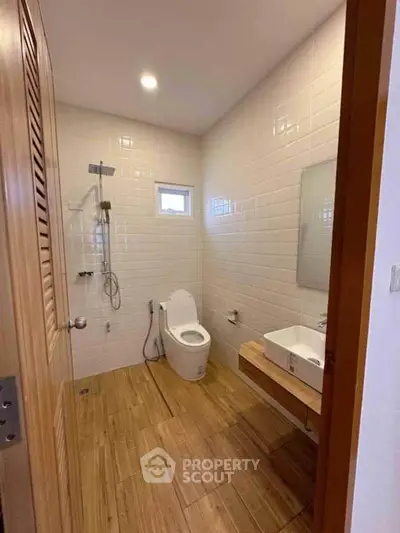 Modern bathroom with wooden flooring and sleek fixtures in a contemporary home.