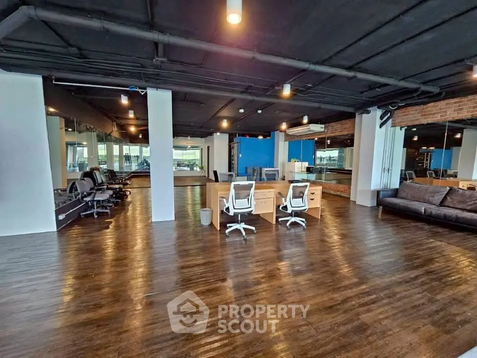Spacious modern office space with sleek wooden flooring and stylish furniture.