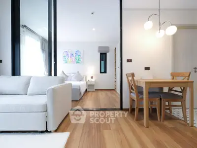 Modern open-plan living room with cozy bedroom and dining area, featuring elegant wooden flooring and stylish decor.