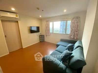 Cozy living room with modern sofa and wall-mounted TV, bright natural light from window.