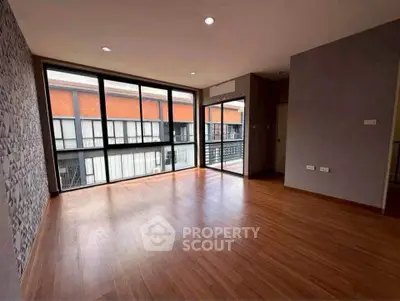 Spacious modern living room with large windows and wooden flooring.