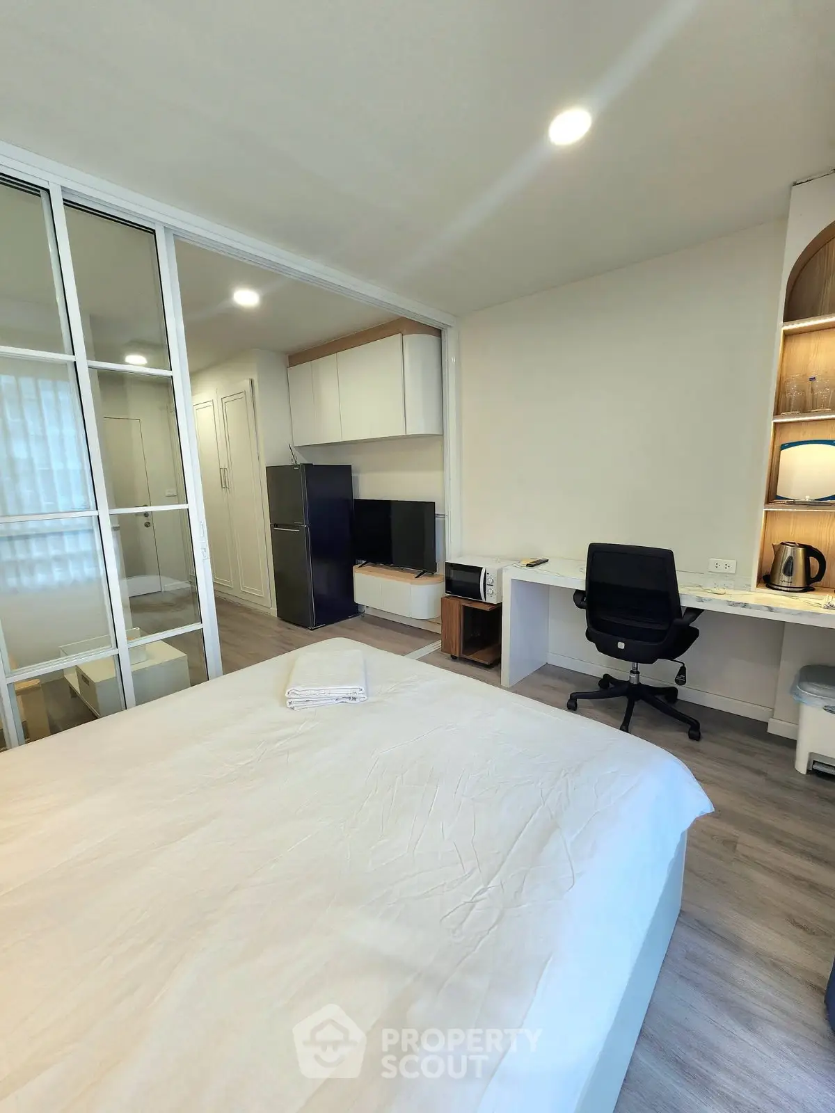 Modern bedroom with workspace and kitchenette in stylish apartment