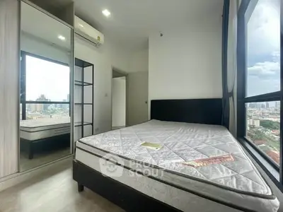 Modern bedroom with city view, featuring a large window and sleek furnishings.