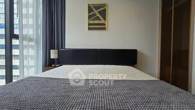 Modern bedroom with stylish decor and large window offering natural light.