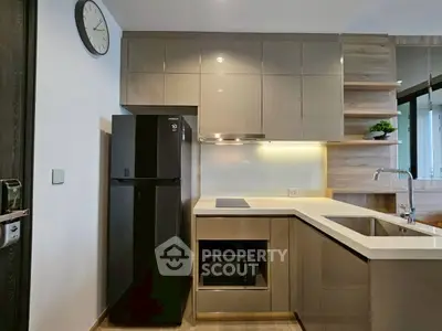 Modern kitchen with sleek cabinets, black fridge, and built-in microwave.