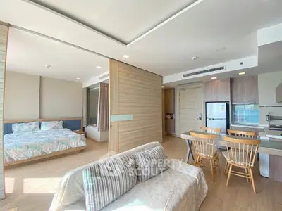 Spacious open-plan living room with modern kitchen and cozy bedroom in a bright apartment.
