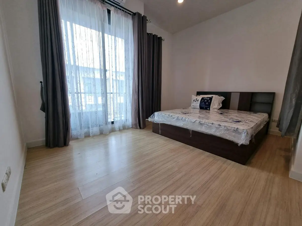 Spacious bedroom with large window and modern wooden flooring