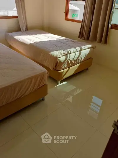 Cozy bedroom with twin beds and natural light, perfect for relaxation.
