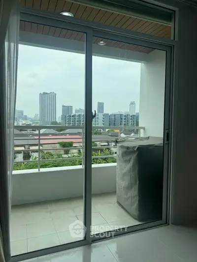 Modern apartment balcony with city skyline view and sliding glass door.