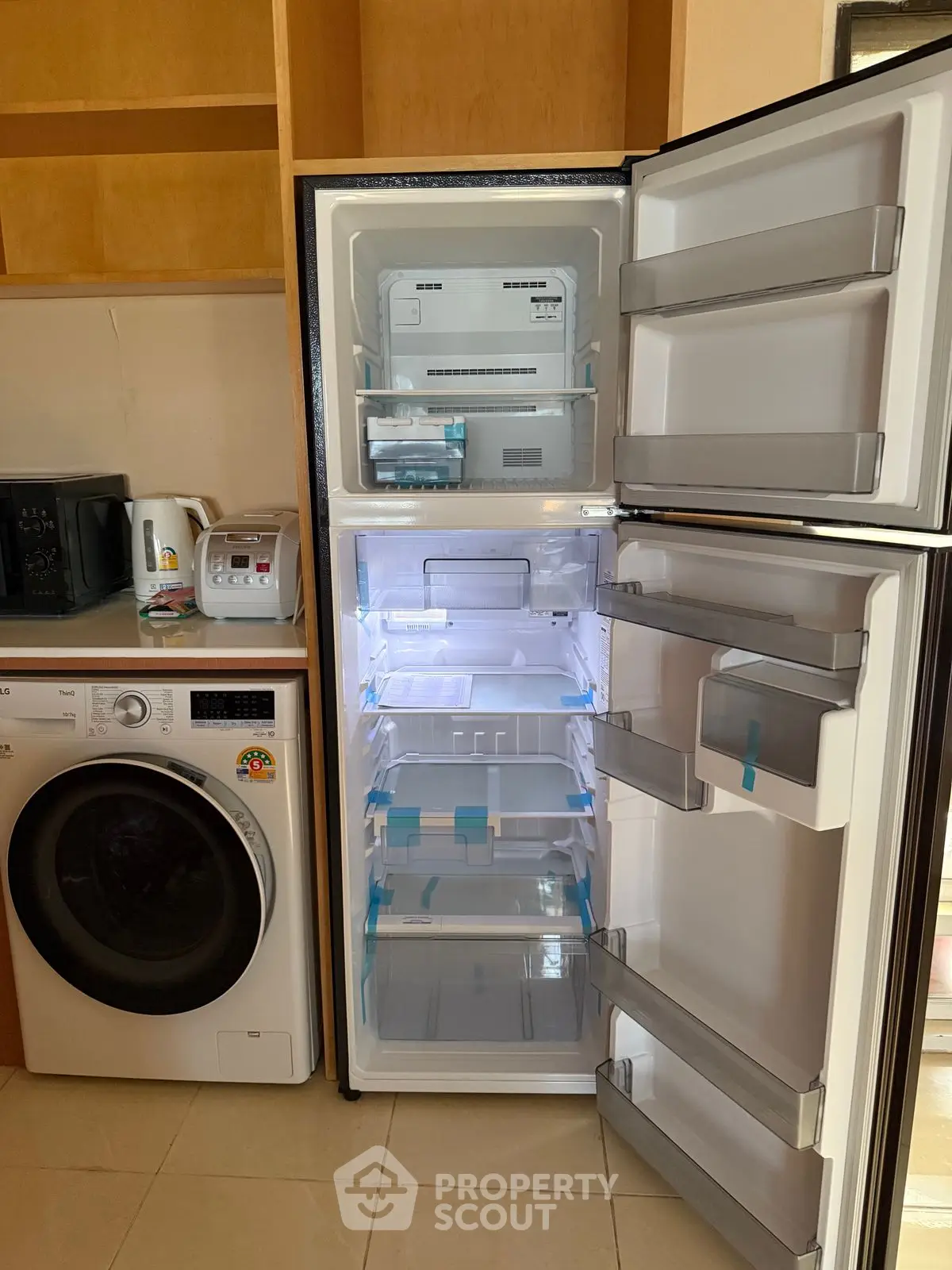 Modern kitchen with new fridge and washing machine, ideal for efficient living.