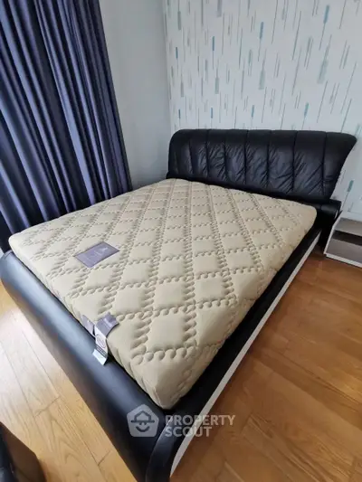Modern bedroom with stylish black leather bed and wooden flooring