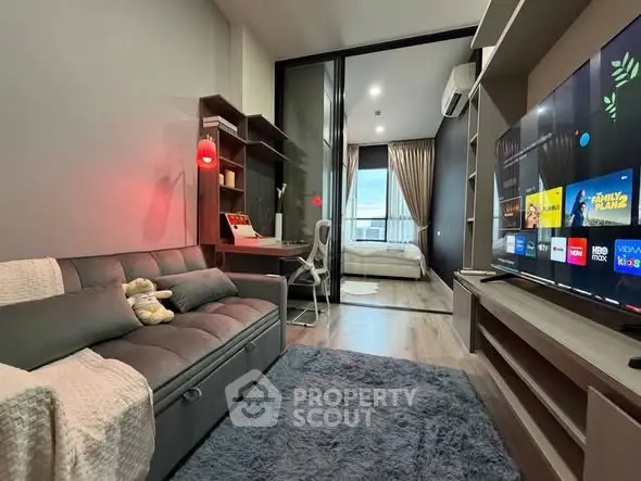 Modern living room with cozy sofa and entertainment setup leading to a stylish bedroom.