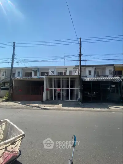 Charming townhouse exterior with gated parking in a sunny neighborhood.