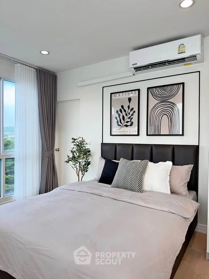 Modern bedroom with stylish decor and large window offering natural light.