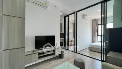 Modern open-plan living room with sleek furniture and large windows in a stylish apartment.