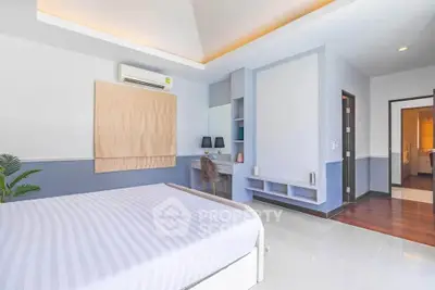 Spacious modern bedroom with elegant decor and ample natural light, featuring a cozy study nook.