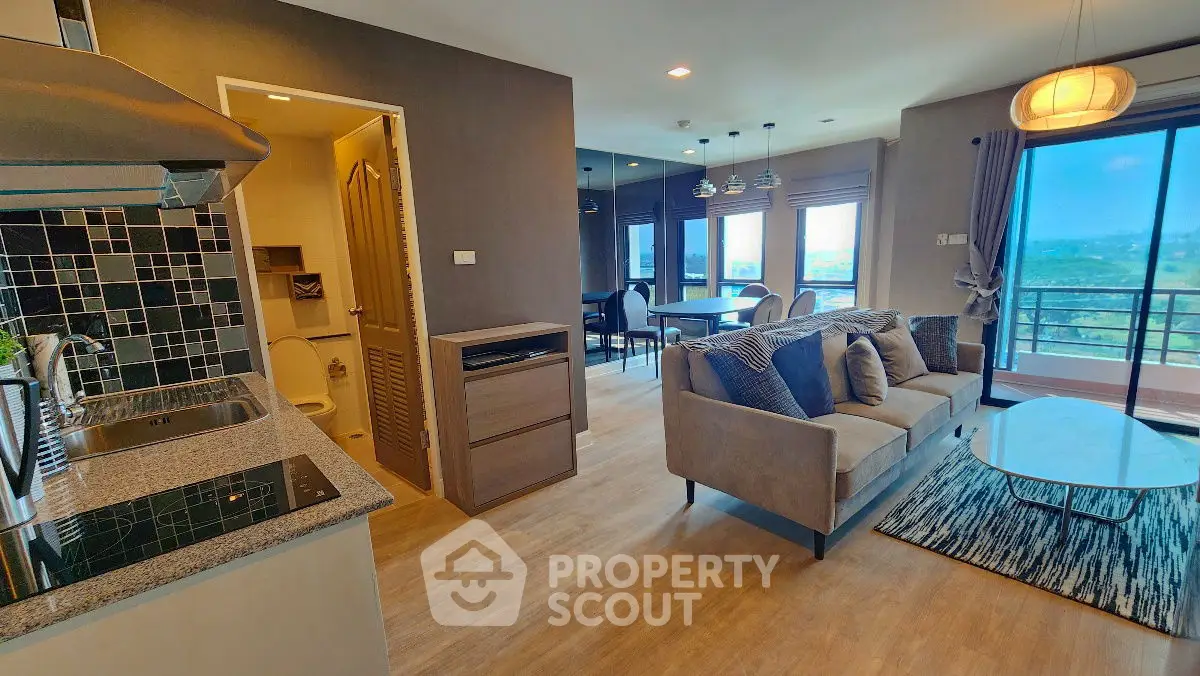 Modern open-plan living room with kitchen and balcony view