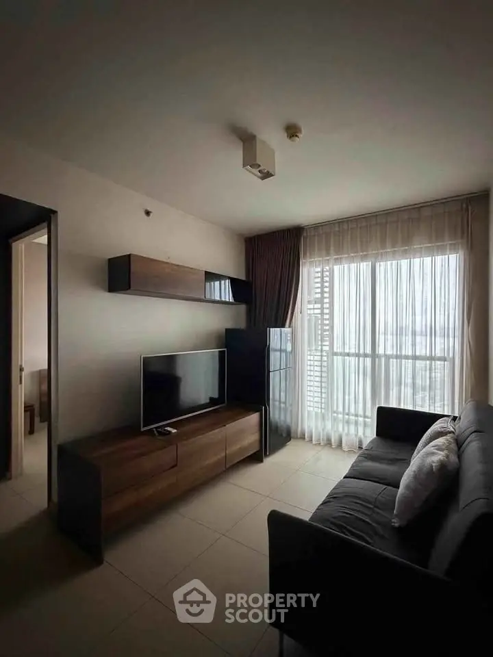 Modern living room with sleek furniture and large window offering natural light.