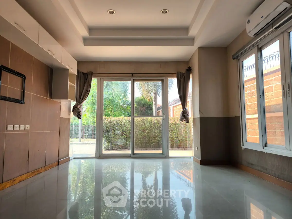 Spacious living room with large windows and garden view, perfect for natural light lovers.