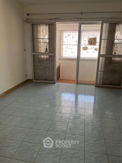 Spacious empty room with tiled floor and large windows for natural light.