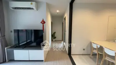 Modern living room with sleek TV setup and dining area in contemporary apartment.