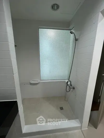 Modern minimalist bathroom with frosted glass window and sleek shower design.