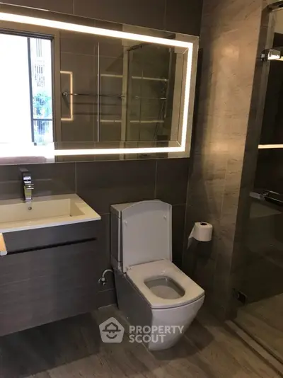 Modern bathroom with sleek fixtures and illuminated mirror in a stylish apartment.