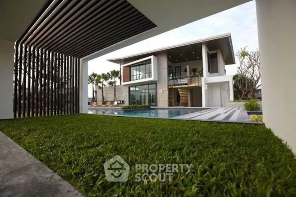 Luxurious modern home with pool and lush garden, showcasing stunning architectural design and spacious outdoor living area.