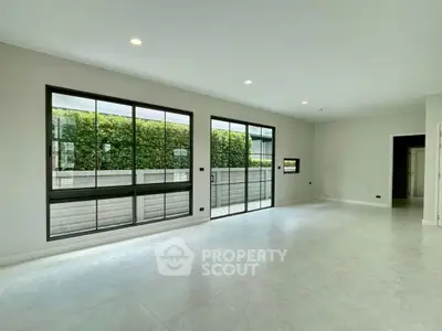 Spacious modern living room with large windows and garden view, perfect for natural light lovers.
