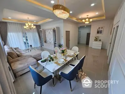 Luxurious open-plan living and dining area with elegant chandelier and modern furnishings.