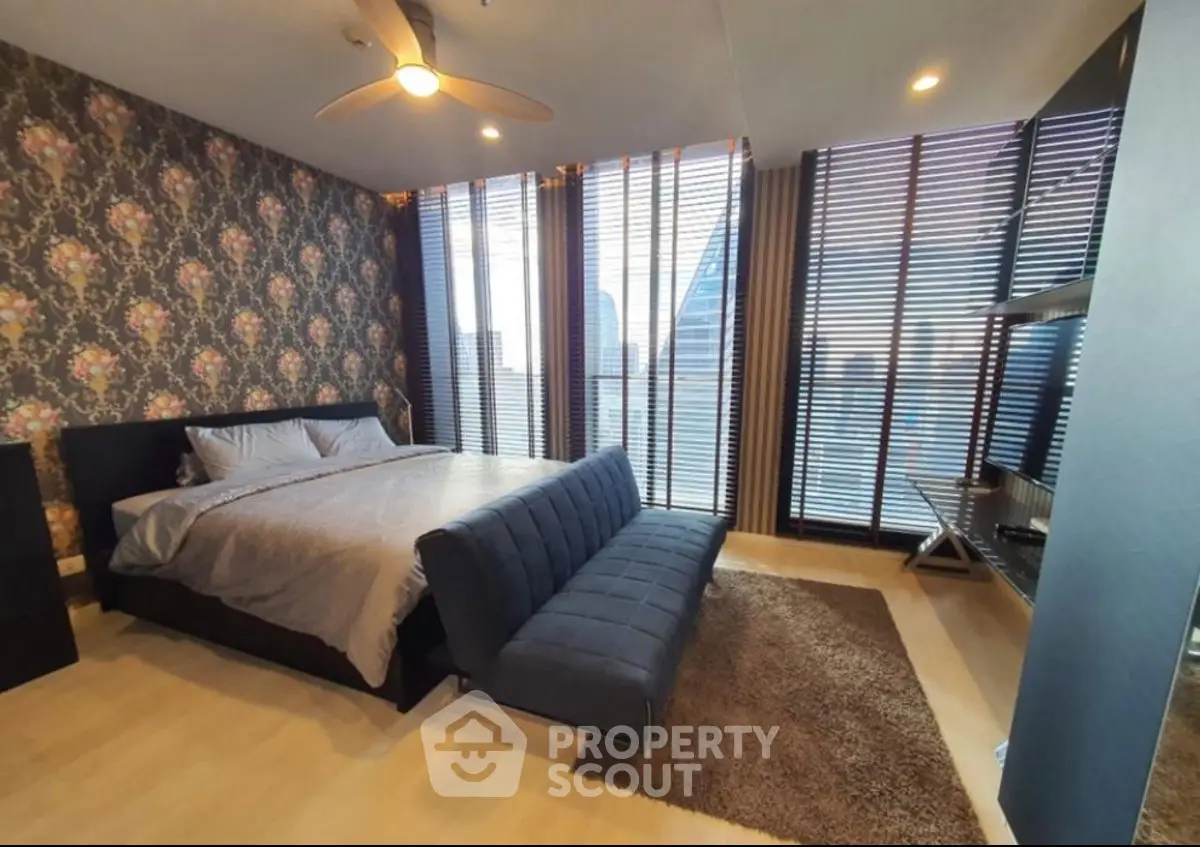 Luxurious bedroom with floor-to-ceiling windows and modern decor in high-rise apartment.