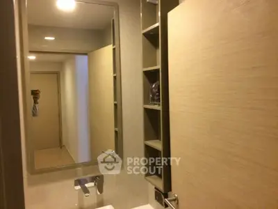 Modern bathroom with sleek mirror and built-in shelving, featuring contemporary fixtures.