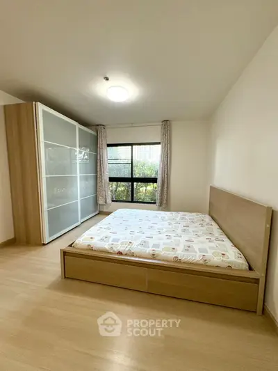 Spacious bedroom with large window and modern wardrobe in a serene setting.