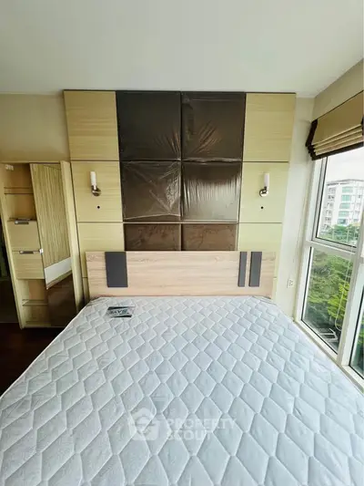 Modern bedroom with large window and stylish headboard in a high-rise apartment.