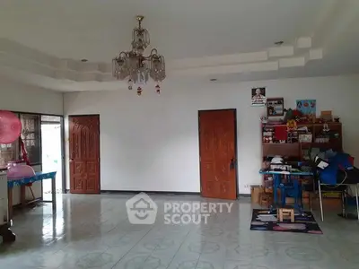 Spacious living room with chandelier and tiled flooring in a cozy home.