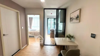 Modern apartment interior with dining area and view into bedroom, featuring sleek design and natural light.