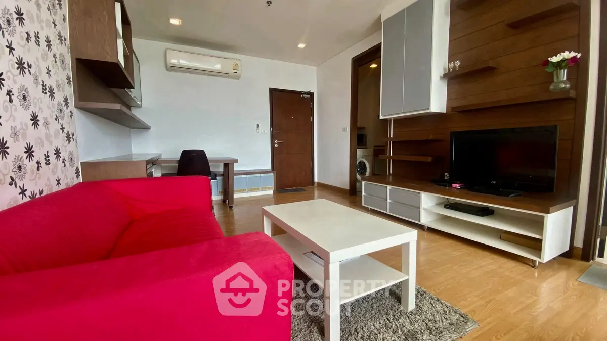 Stylish living room with red sofa, modern TV unit, and wooden flooring.