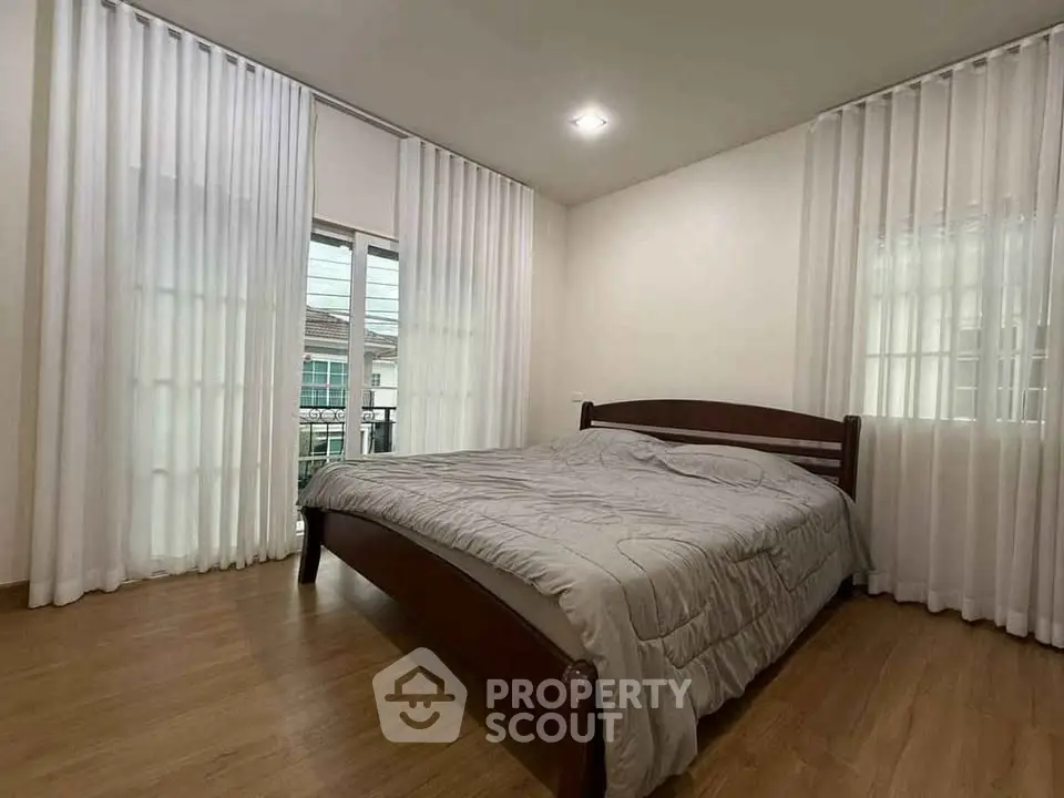 Spacious bedroom with wooden flooring and large windows for natural light.