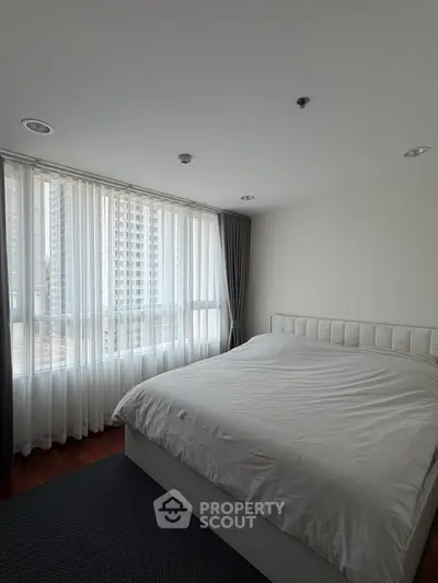 Spacious bedroom with large windows offering city views in modern apartment