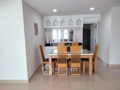 Modern dining area with elegant wooden chairs and glass-top table in a bright, spacious room.