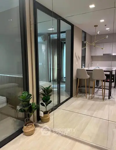 Modern apartment interior with stylish kitchen and mirrored wall, featuring elegant lighting and cozy seating.
