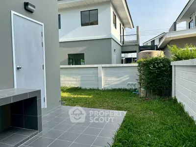 Modern backyard with tiled patio and lush green lawn in a suburban home setting.